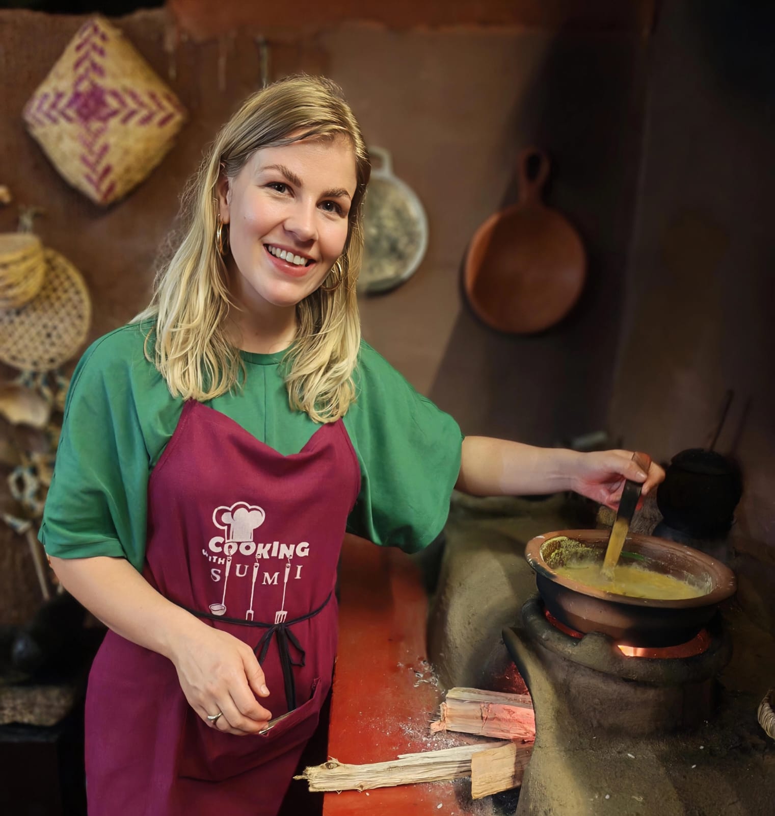 Guest stirring clay pot over traditional firewood stove