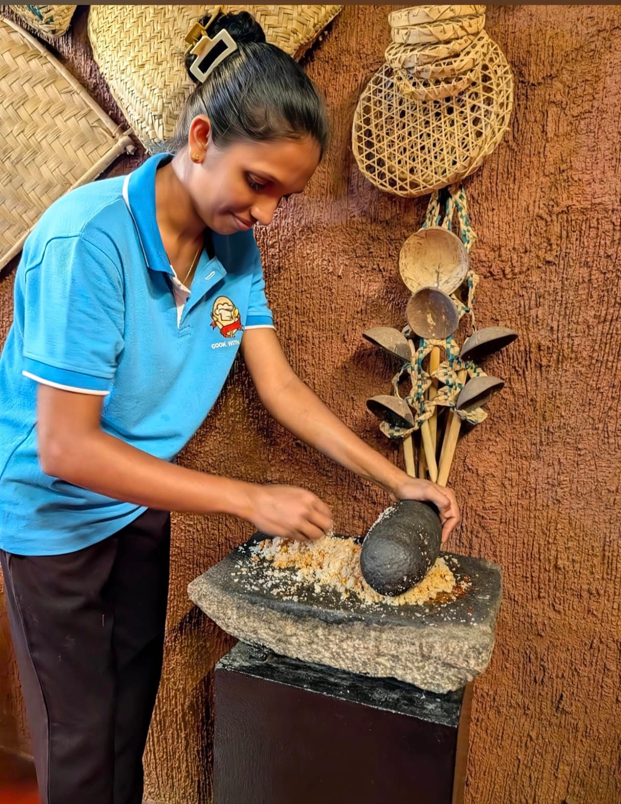 Staff member grinding fresh coconut and spices on granite Miris Gala stone